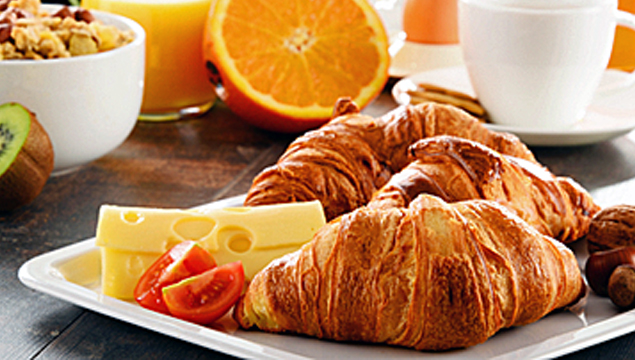 breakfast picture of croissant, cheese, fruit, muesli, juice and coffee